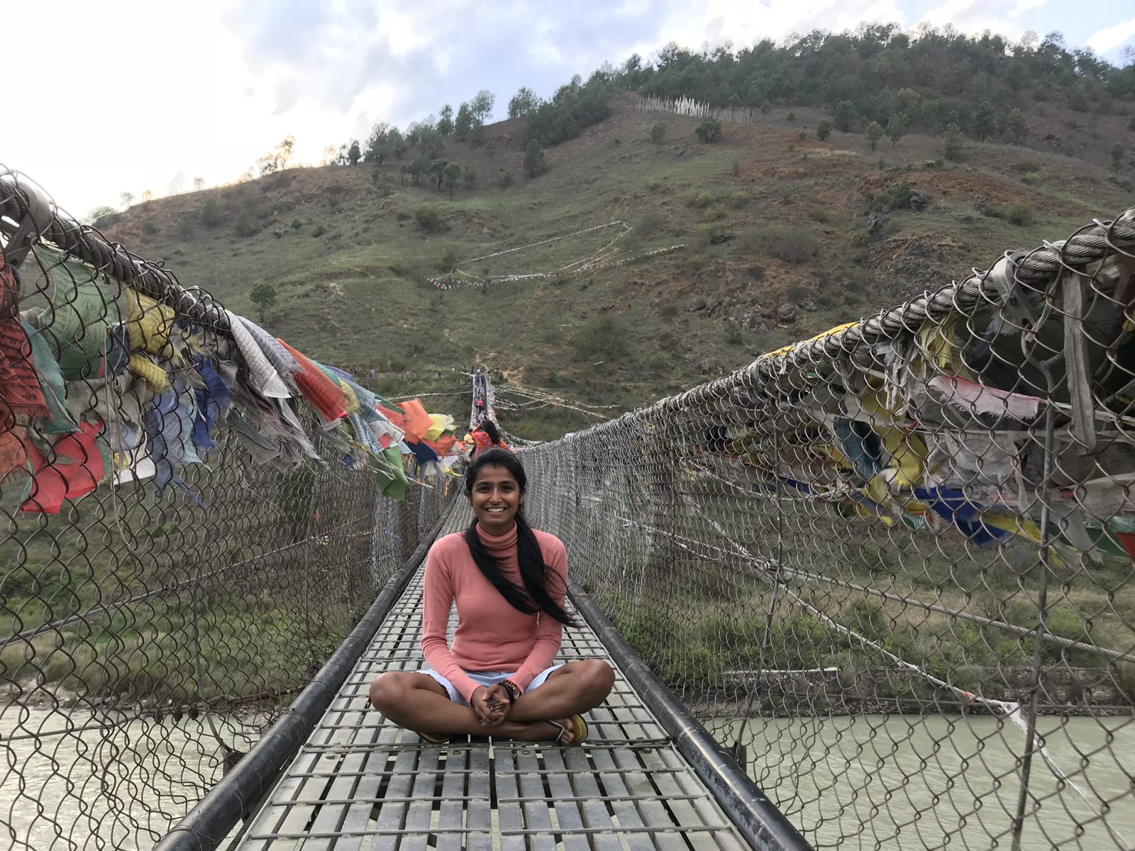 Sloka on a suspension bridge with prayer flags in Bhutan